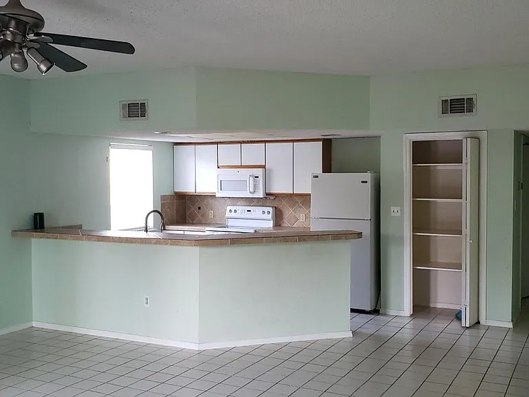 Open the door and look into a very large living area. Kitchen in the back.