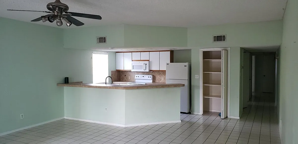 Open the door and look into a very large living area. Kitchen in the back. - 109 E Aries Dr #C