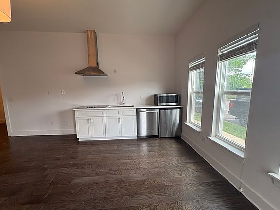 Downstairs is a studio apartment with a stovetop, sink, small refrigerator, dishwasher, and microwave