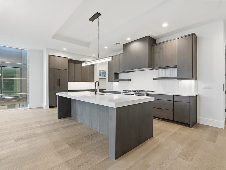 Stunning kitchen with oversized island waterfall island, custom cabinetry, and high-end modern finishes