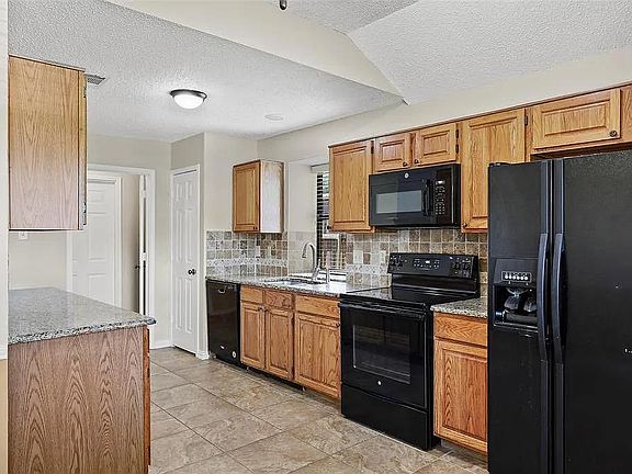 Kitchen view from breakfast area, newer stove (radiant cooktop) and dishwasher. Refrigerator side by side, ice and water in door
