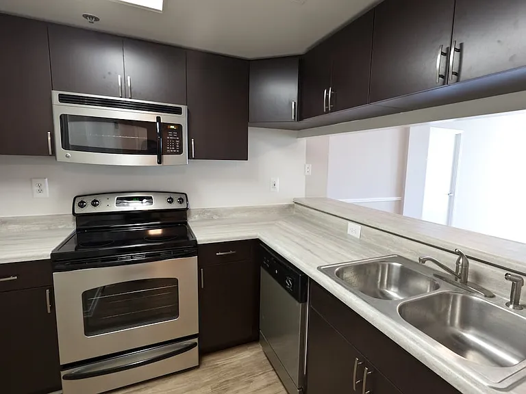 Classic Package II kitchen with grey countertops, espresso cabinetry, stainless-steel appliances, and hard surface flooring (select homes)