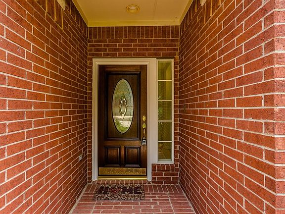 The covered brick front porch and wood with decorative leaded glass front door welcome you in.