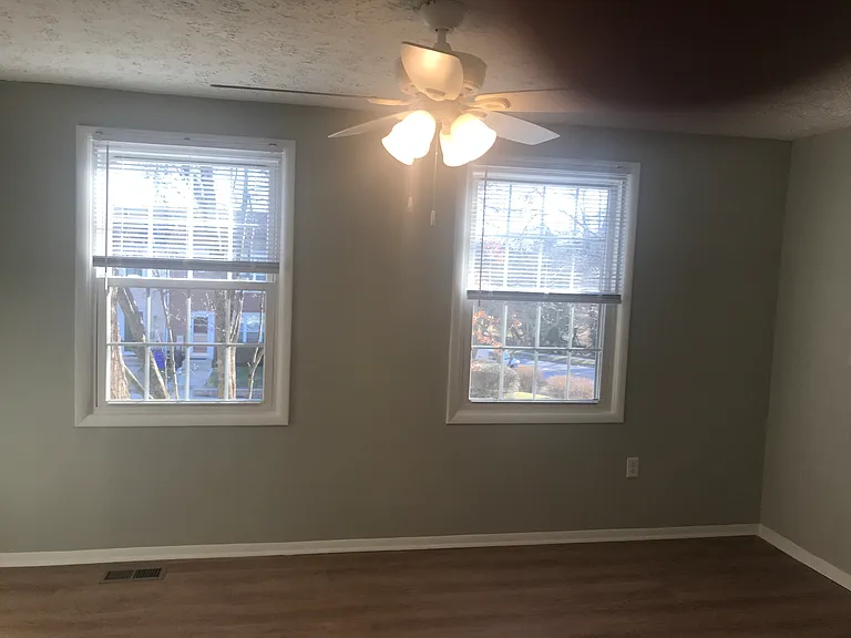 Street facing windows and ceiling fan in the master suite