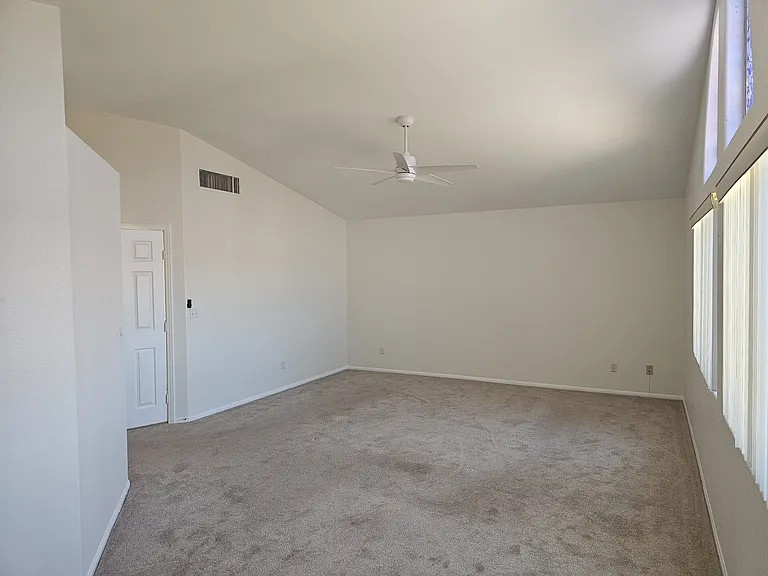 A spacious primary bedroom offers, lofty vaulted ceilings, ceiling fan and a space for sofa or desk