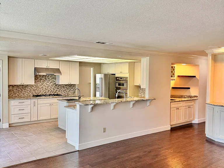 Open-concept layout featuring the kitchen, high-top seating bar, wet bar, and family room