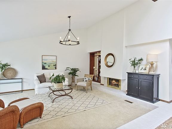 This stunning, spacious living room greets you as you enter the home. It boasts a lovely gas fireplace, plush carpeting, gorgeous lighting and lovely open shelving.
