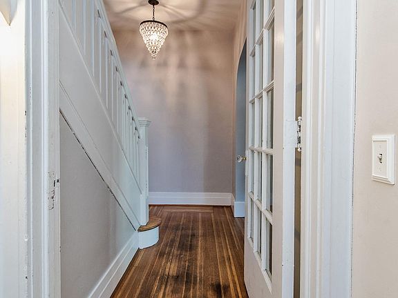 Entryway into property with beautiful staircase, fresh paint and crystal chandelier.