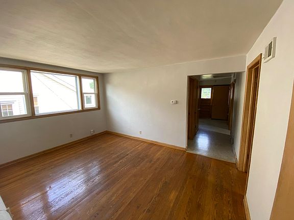 Large sunny living room with hardwood floors and picture window.