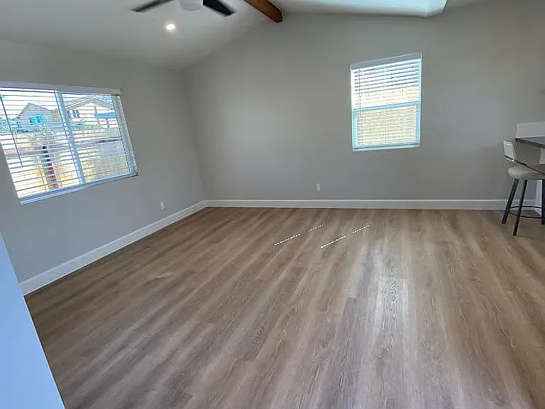 Living room is generous, vinyl plank throughout, no carpet, exposed wood beam at vaulted ceiling, great open concept from kitchen.