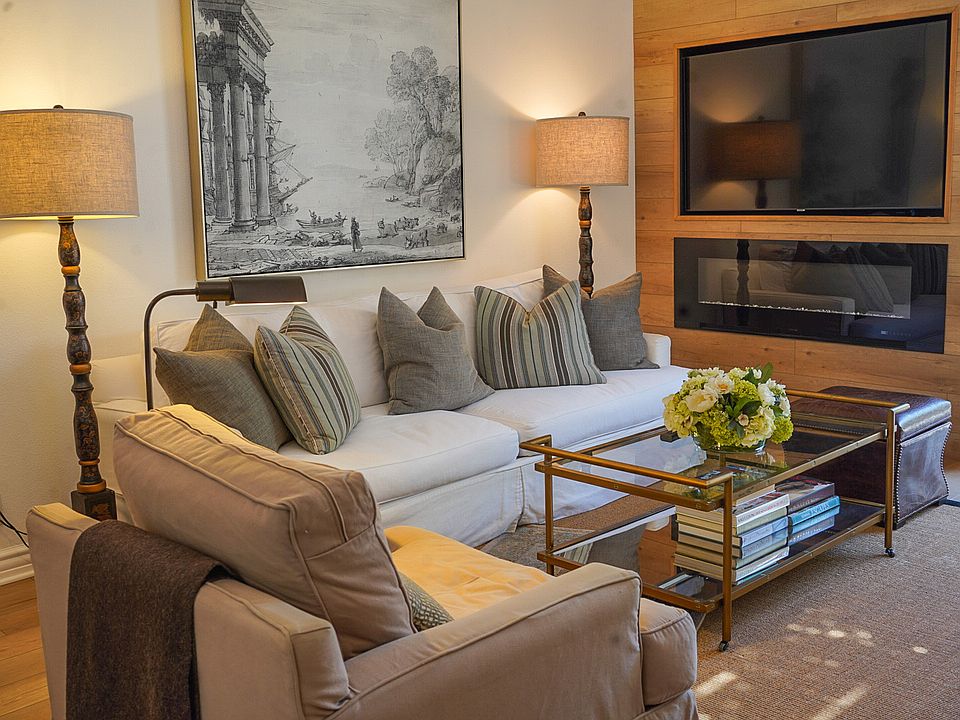 White linen slip covered couch with electric fireplace and built in TV. Looking out to your private and secluded patio with fountain.