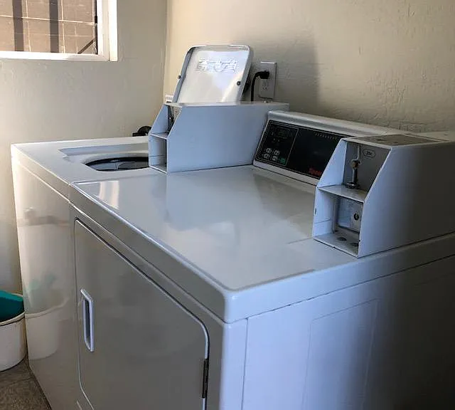 Shared coin-operated washer and dryer in the separate enclosed laundry room