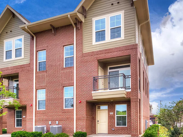 The exterior of a North 680 townhouse. The walls are primarily red brick with tan siding near the top.