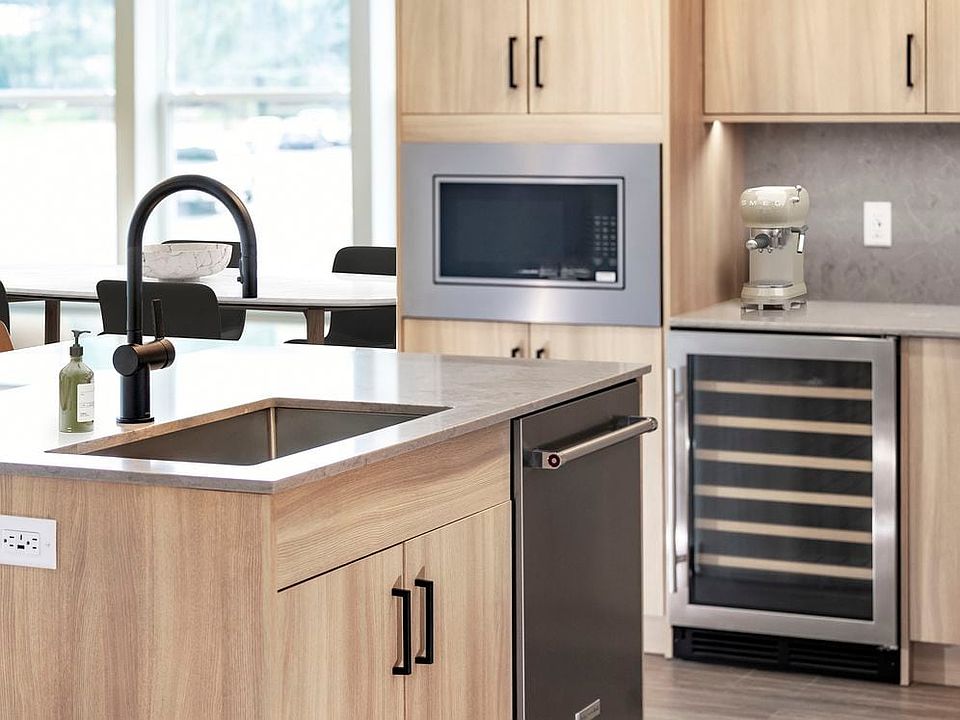 Signature Collection kitchen with stainless steel appliances (wine fridge included), quartz countertops, quartz tile backsplash, oak cabinetry, and hard-surface flooring