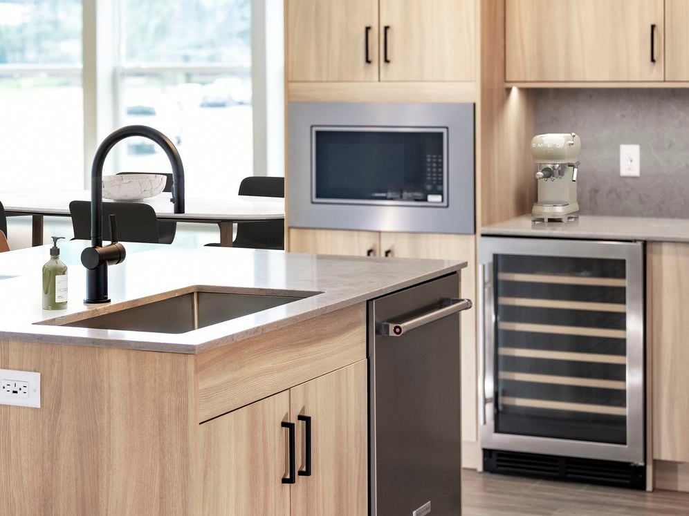Signature Collection kitchen with stainless steel appliances (wine fridge included), quartz countertops, quartz tile backsplash, oak cabinetry, and hard-surface flooring