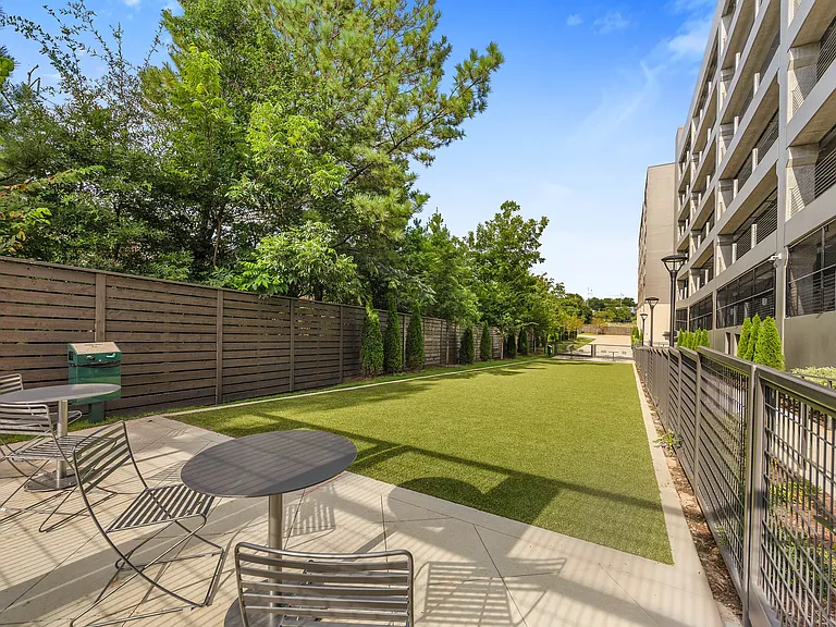 Charming outdoor area with modern patio seating, manicured lawn, and lush greenery, ideal for relaxation and social gatherings.