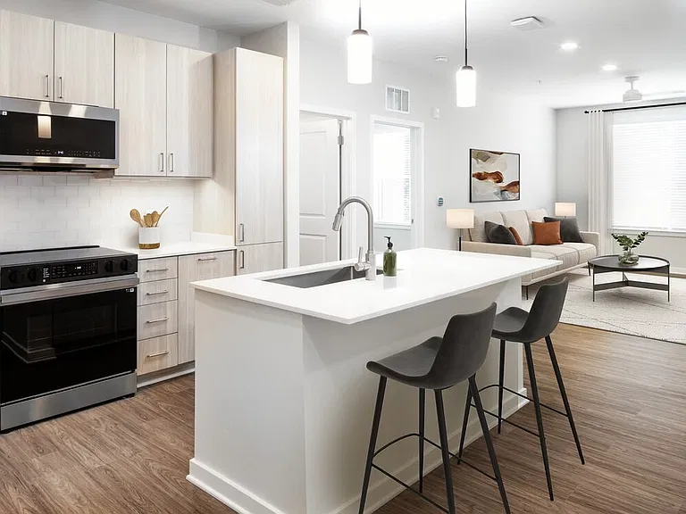 Design Collection II kitchen with stainless steel appliances, cream quartz countertops, oak cabinetry, and hard surface flooring
