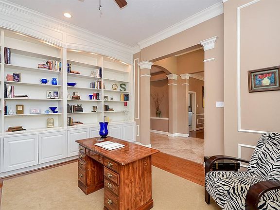 The study has hard wood floors, built in book shelves, tall ceilings, crown molding, plantation shutters, and recessed lighting.