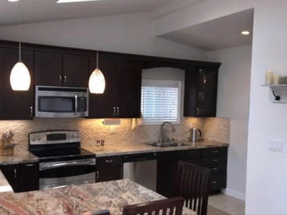 Kitchen with barstools, gooseneck faucet, garbage disposal, stainless steel appliances, microwave, fridge
.