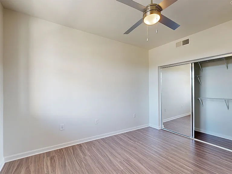 Spacious apartment bedroom with wood-style flooring.