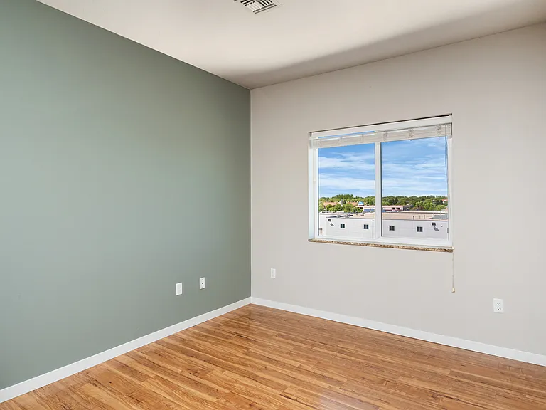 Bright and airy room with a large window showcasing scenic views, complemented by smooth wooden floors and a stylish accent wall. Bright and airy room with a large window showcasing scenic views, complemented by smooth wooden floors and a stylish accent w