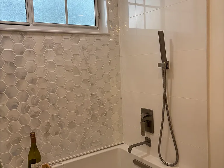 Bathtub/shower with rainfall shower head and handheld sprayer in the guest bathroom