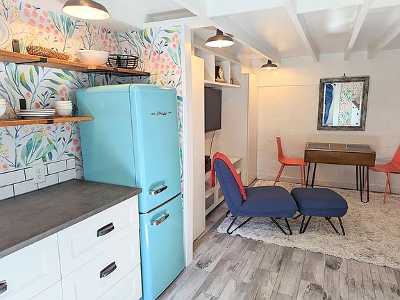 Tile floor throughout, wallpaper in kitchen area, farmhouse lighting and exposed ceiling beams.