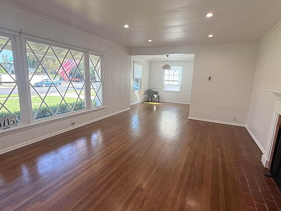 Living room and dinign room with original hardwood floors and newer recessed lighting.