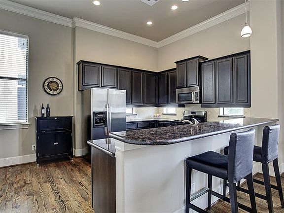 Kitchen has granite counters, stainless appliances, under counter lighting, and dark, rich custom cabinets.