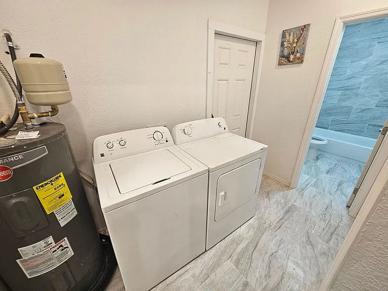 Dedicated laundry area with a full-size washer and dryer, set on durable flooring with convenient access to nearby rooms.