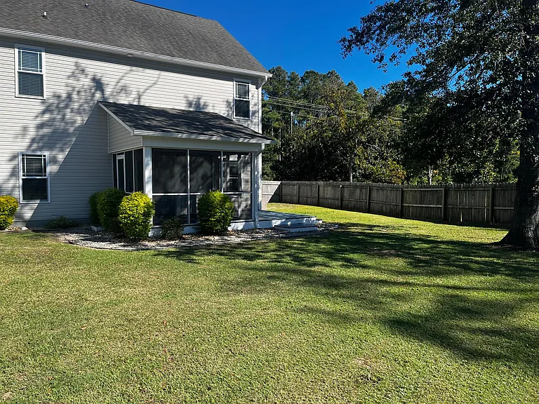 Wide view of the screened porch, deck, and large fenced lawn.