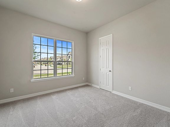 The third bedroom features plush carpet, fresh paint, closet, and a large window that lets in plenty