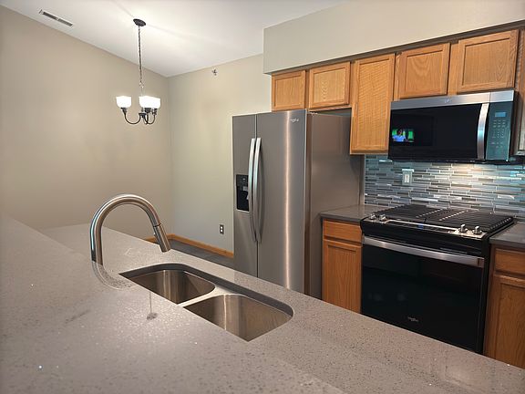 Kitchen with new appliances, quartz countertops, luxury vinyl tile and tile backsplash