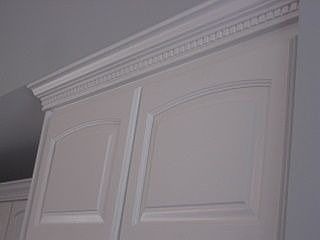 Crown moulding encases cabintes around kitchen with some illuminated crown.