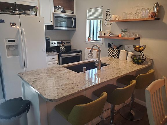 Newly renovated kitchen featuring large granite island with seating, new stainless appliances, and plenty of storage.
