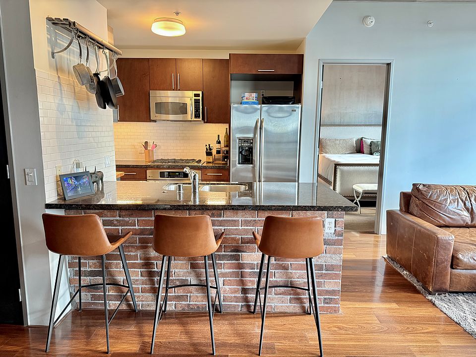 Kitchen with updated stainless steel appliances. Refrigerator, microwave, oven.