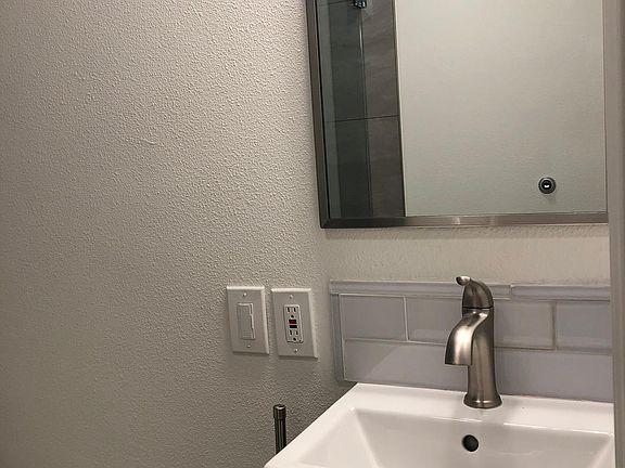 Bathroom sink and mirror with glass tile backsplash.