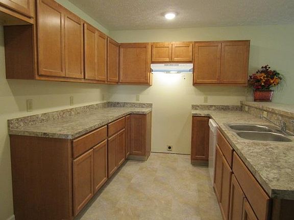 Wow! What a nice kitchen. The faux granite gray/brown countertops look great on the light colored brown cabinets and compliment the cream colored walls. Stainless steel sink, faucet with sprayer and garbage disposal. Appliances will be all white: hood