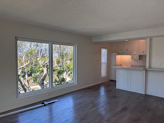 Bright iving room with new windows, breakfast bar, and kitchen (blinds on floor have since been installed)