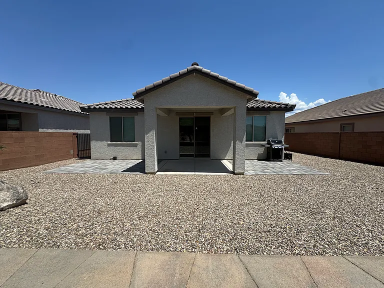 Rear exterior view featuring a covered patio and spacious, low-maintenance backyard