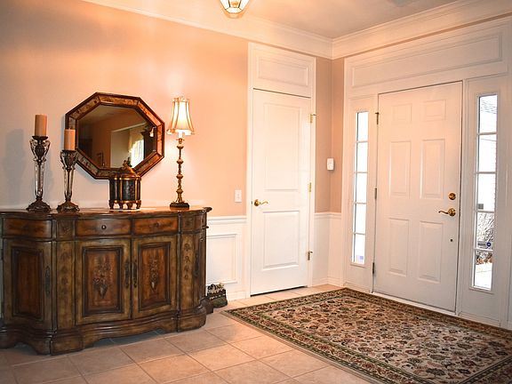Beautiful foyer with wainscoting, crown molding and trimmed doors.