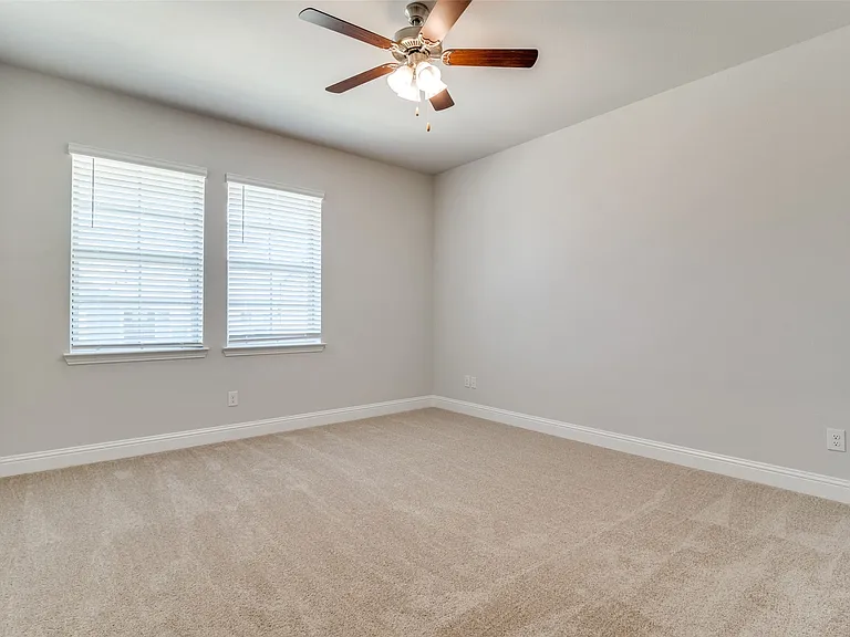 Neutral tone walls in a spacious room featuring a ceiling fan with integrated lighting