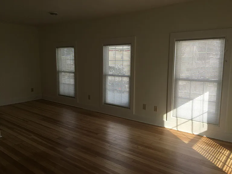 Bright upper level bedroom with hardwood flooring.