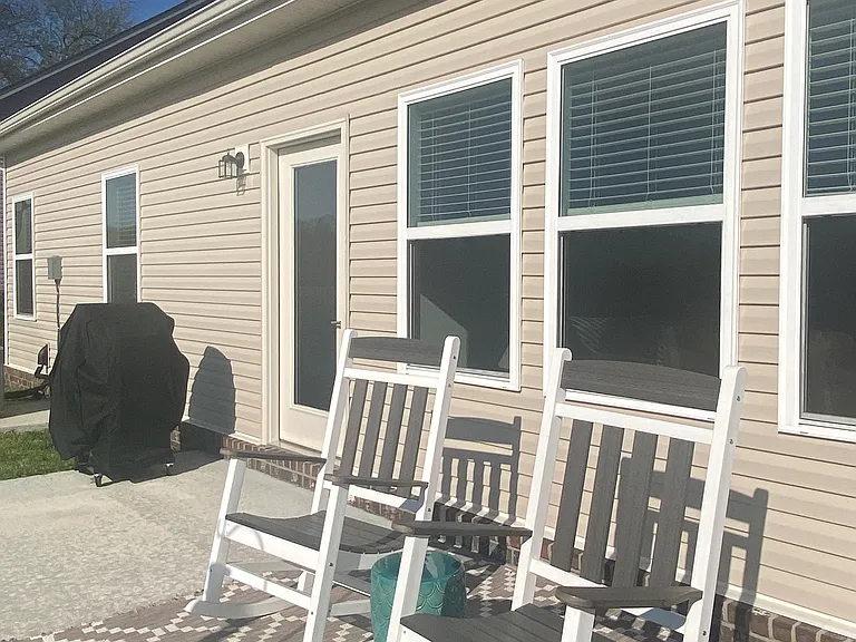 Backyard patio with 2 large comfy rocking chairs and a grill.