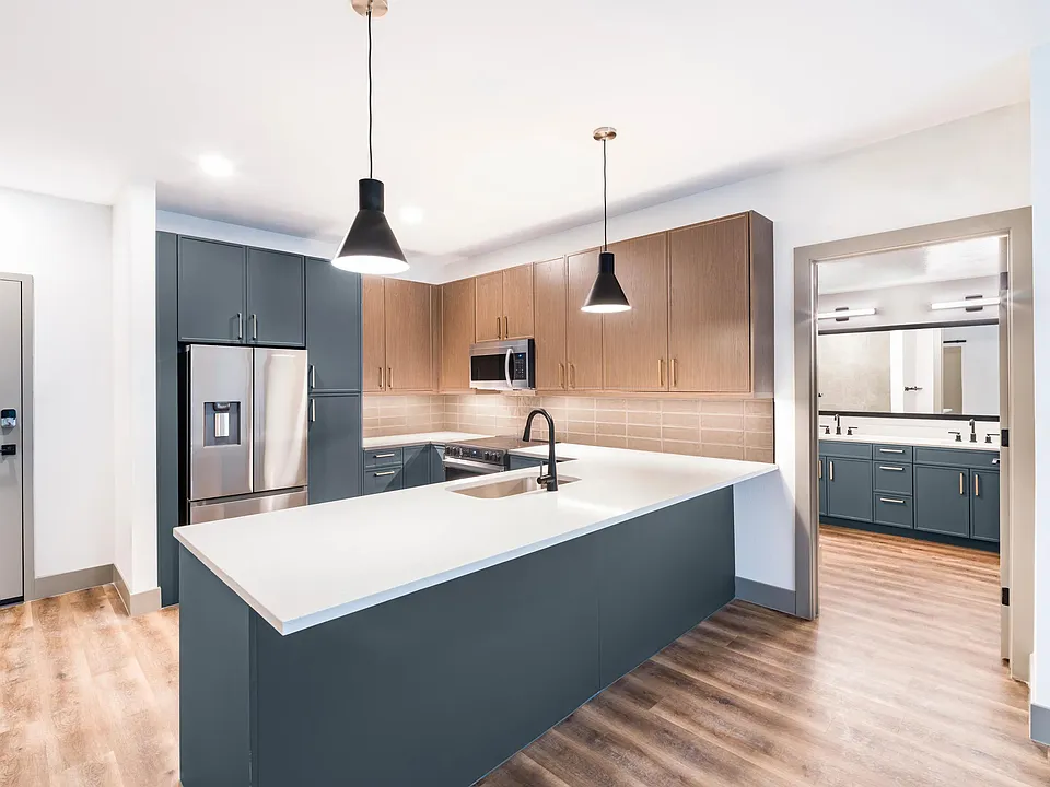 A clean, contemporary kitchen with bold cabinetry, generous counter space, and designer lighting.