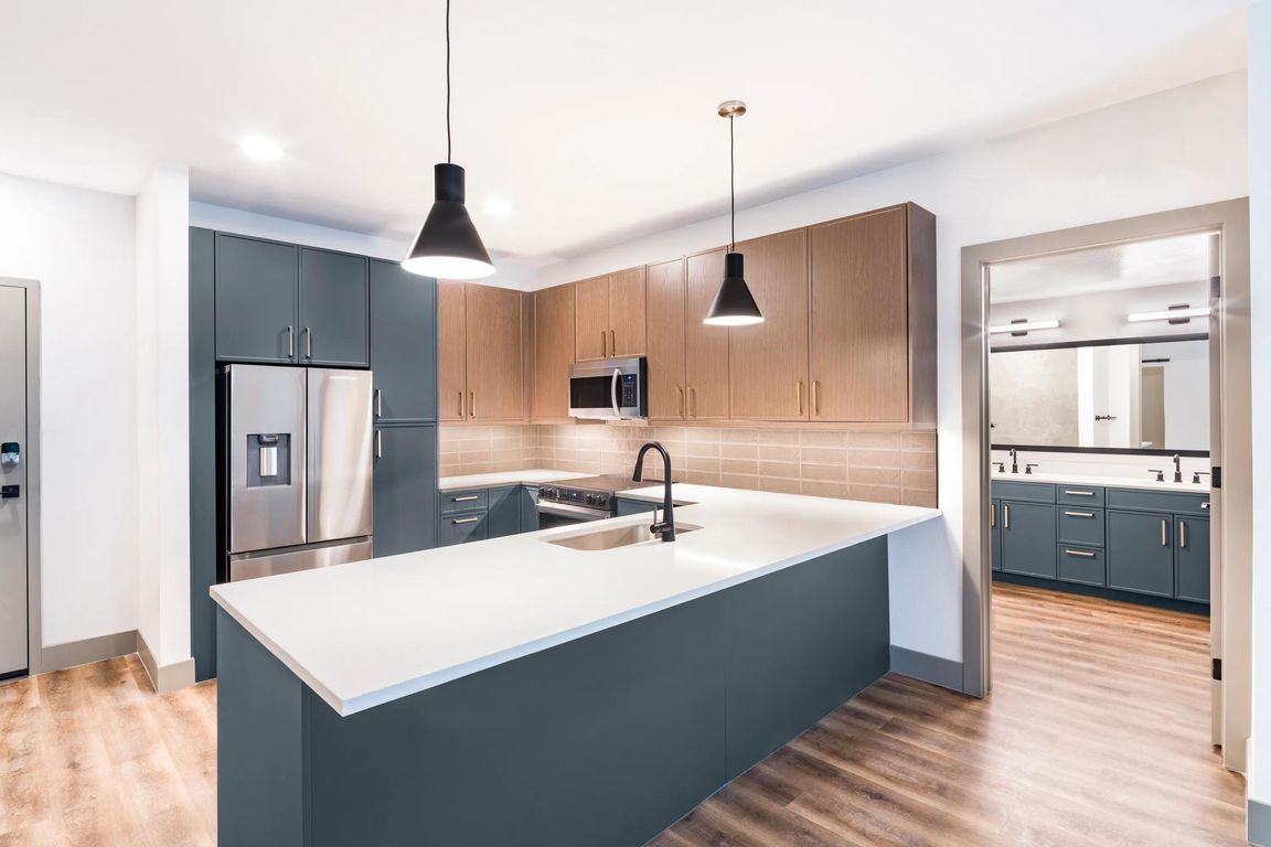 A clean, contemporary kitchen with bold cabinetry, generous counter space, and designer lighting.
