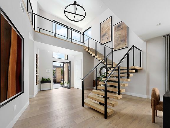 A modern and minimalist entryway with a striking spiral staircase, large windows, and a mix of natur