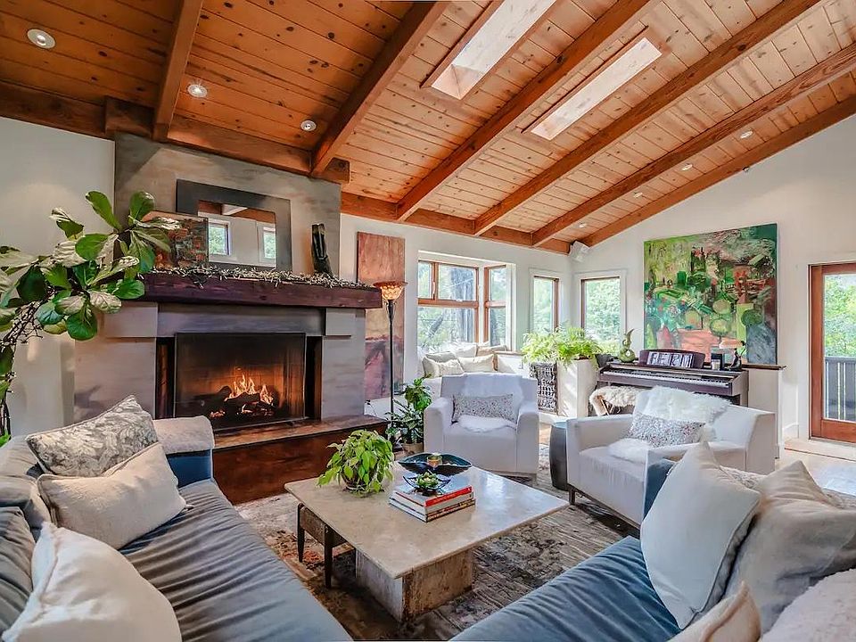 Main living area with gas fireplace and view of the Mill Valley hills, piano and large velvet sectional and plenty of soft blankets .