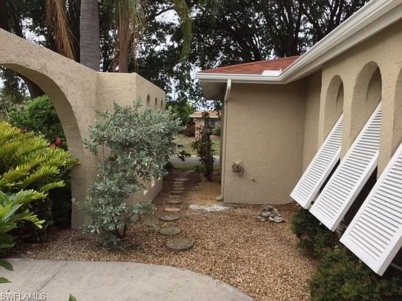 Bahama shutters at front entrance and walkway toward side yard.