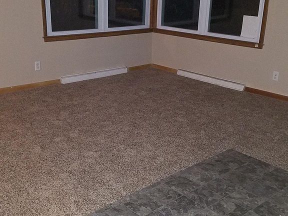 A remnant from the kitchen floor is temporarily covering the carpeting to protect from dirt, etc. This is not part of the living room floor...